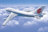 View of an Air China branded plane from above, as it flies above a layer of clouds.