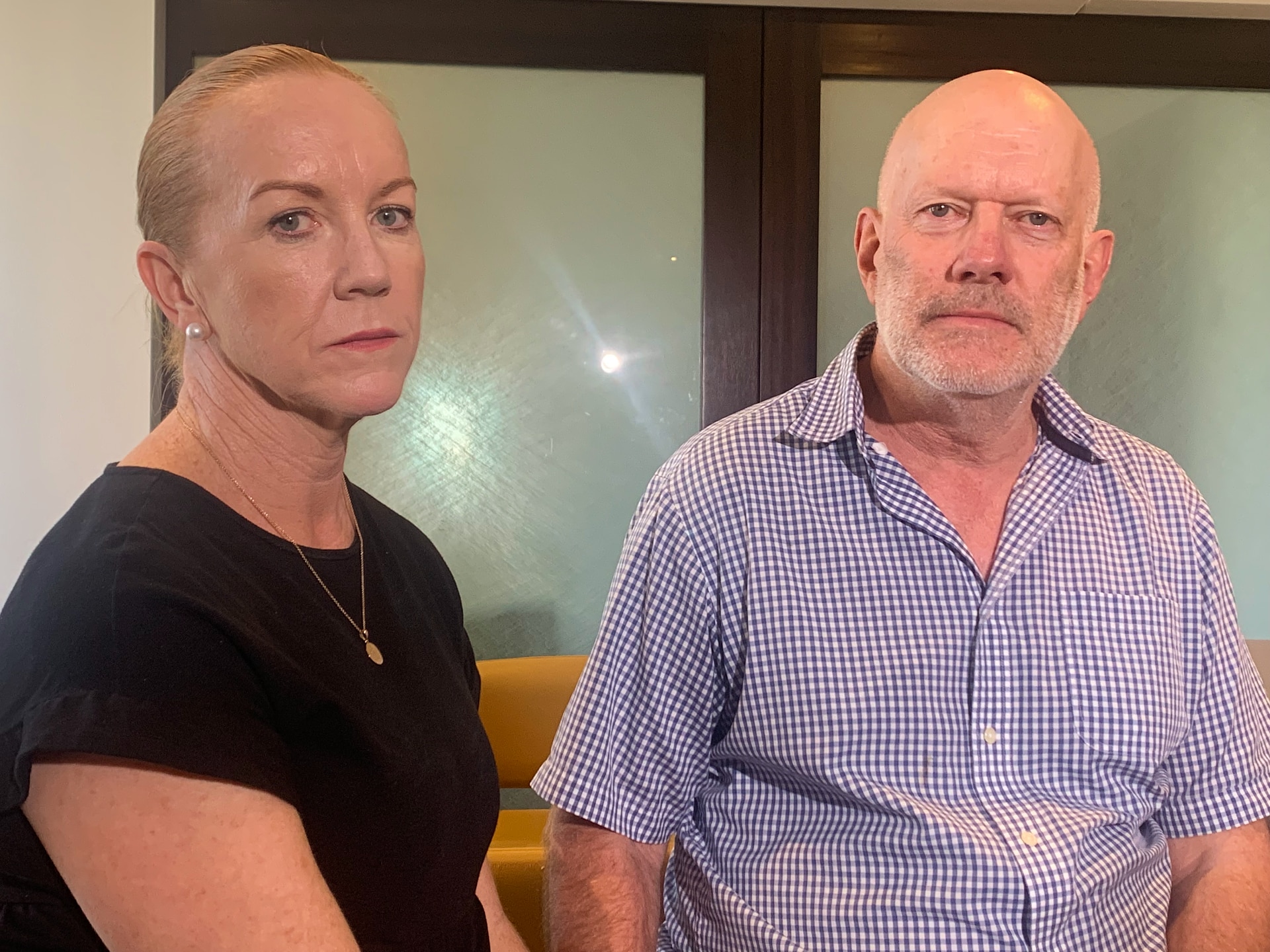 a woman and a man sitting down and looking at the camera