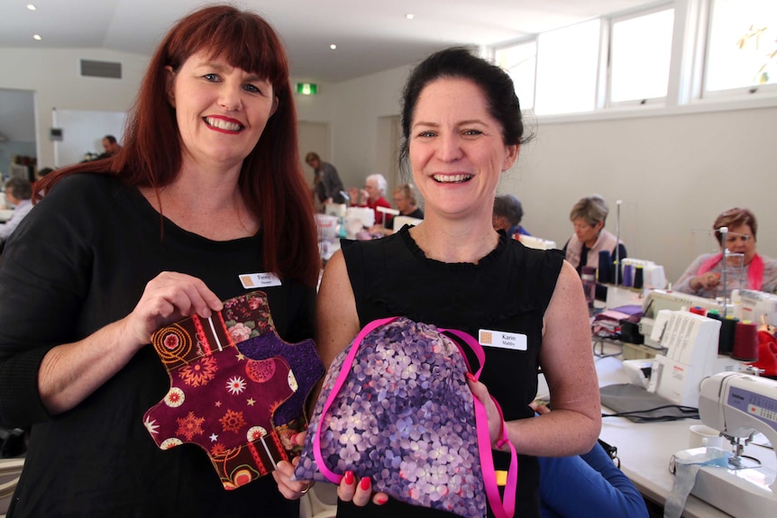 Two women hold sewn sanitary pad holders.