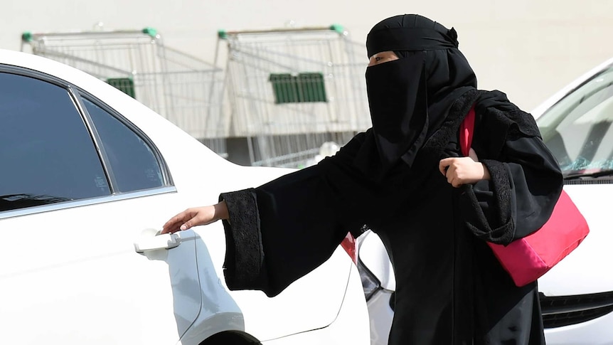 A Saudi woman gets into a taxi at a mall in Riyadh