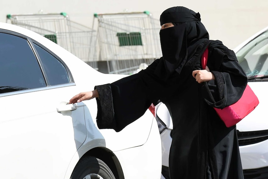 A Saudi woman gets into a taxi at a mall in Riyadh