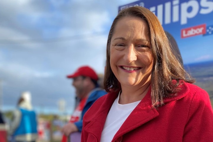 A smiling, dark-haired woman wearing a bright blazer.