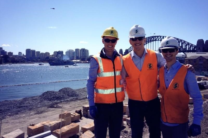 Josh and colleagues wear high-vis and hard hats on a building site in Sydney.