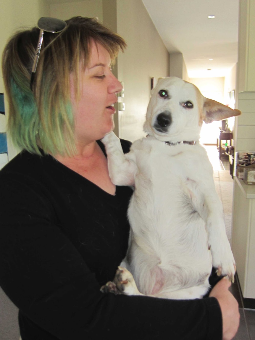 Kirby Littley holds a small white dog.