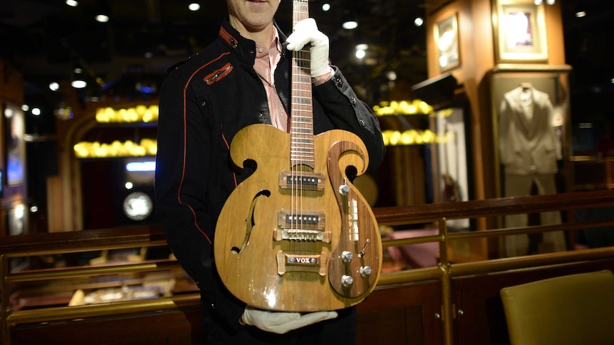 Auction director holds Vox guitar played by Bealtes
