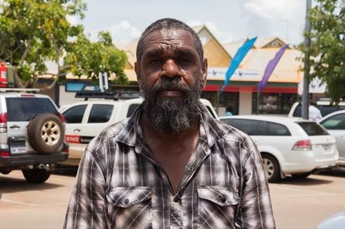An Indigenous man poses for a photo in front of cars in Broome.