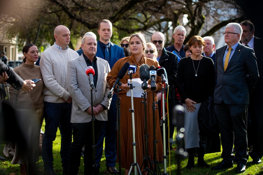 A woman speaks to a media pack