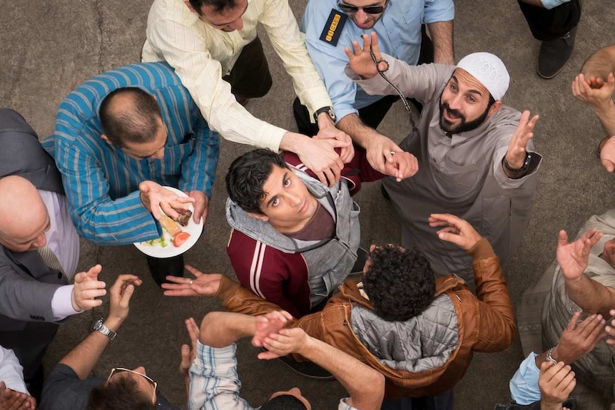 Still image from 2017 film Ali's Wedding, lead actor Osamah Sami stands amongst fellow friends and family celebrating.