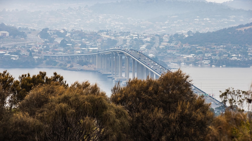 Smoke wreaths the Tasman Bridge and suburbs on the eastern shore.