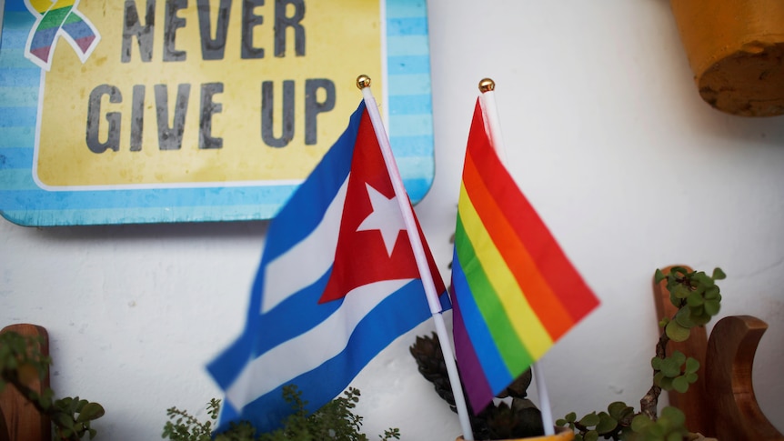 A Cuban flag and a Pride rainbow flag next to each other.
