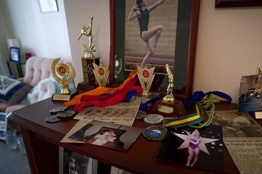 A mantlepiece holding medals on ribbons, photos and newspaper clippings