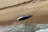 A small yacht ot its side on the beach