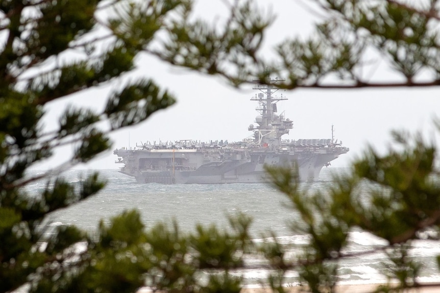 A US aircraft carrier passes Bulcock Beach.