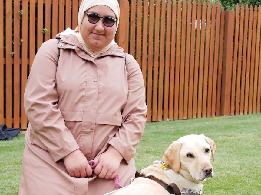 A blind woman in a head scarf with a guide dog