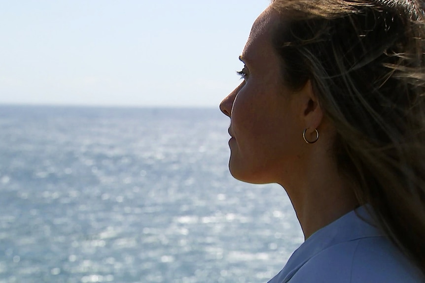 the profile of a woman looking out over the ocean