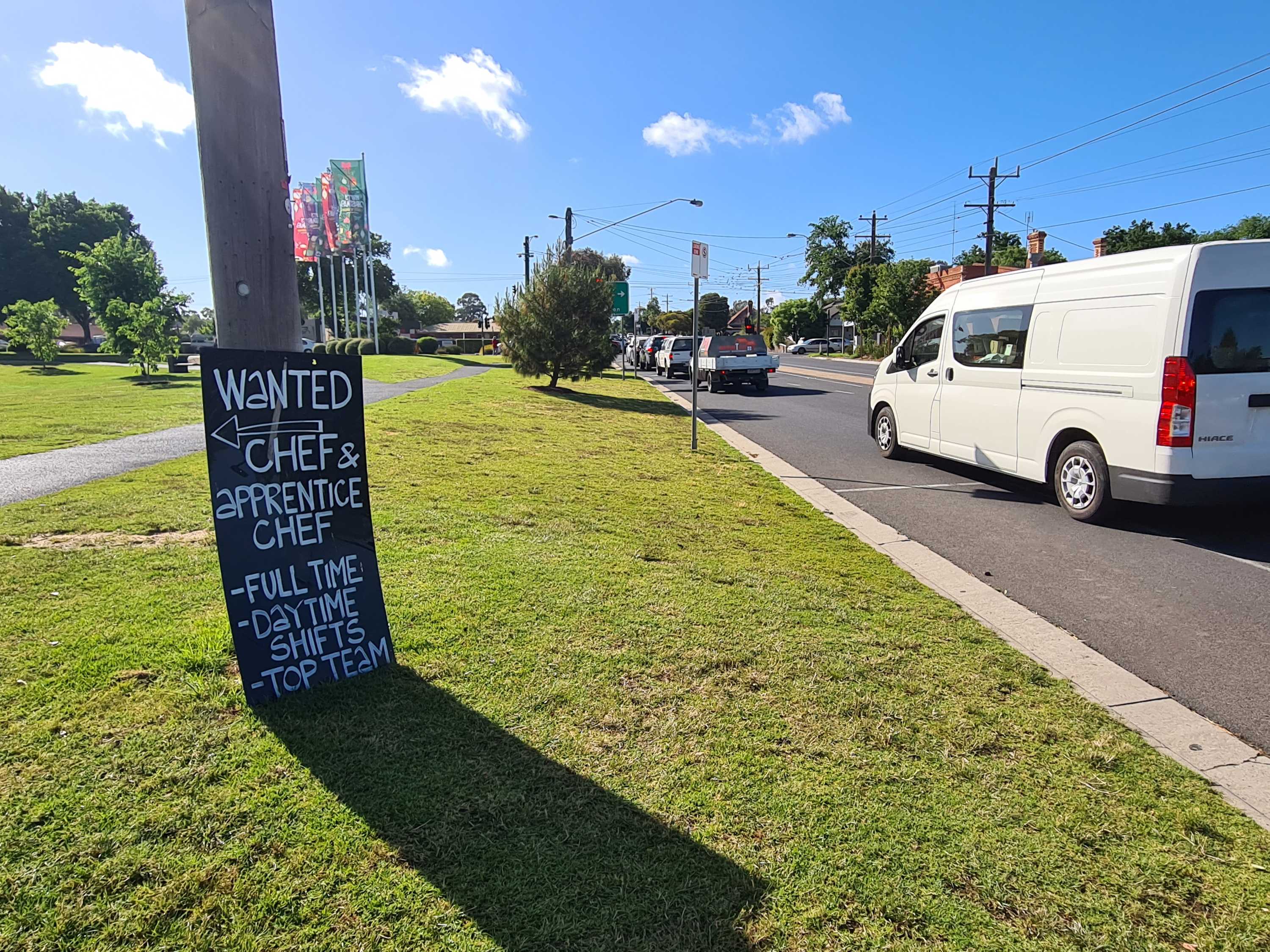 A sign sits by a busy road in Bendigo advertising a chef position and apprentice chef position
