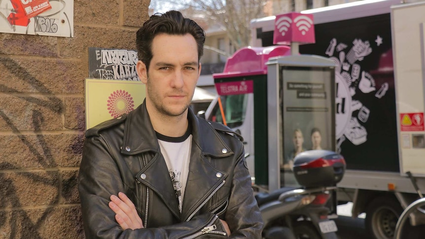 James Lea stands on a busy Melbourne street with his arms crossed.