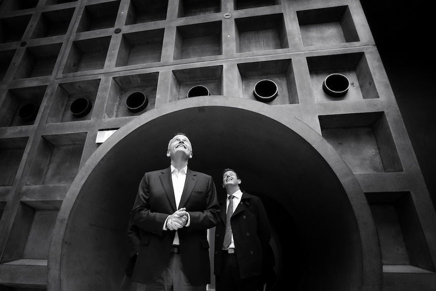 Two men look up and smile as the emerge from a walkway in a black and white photograph