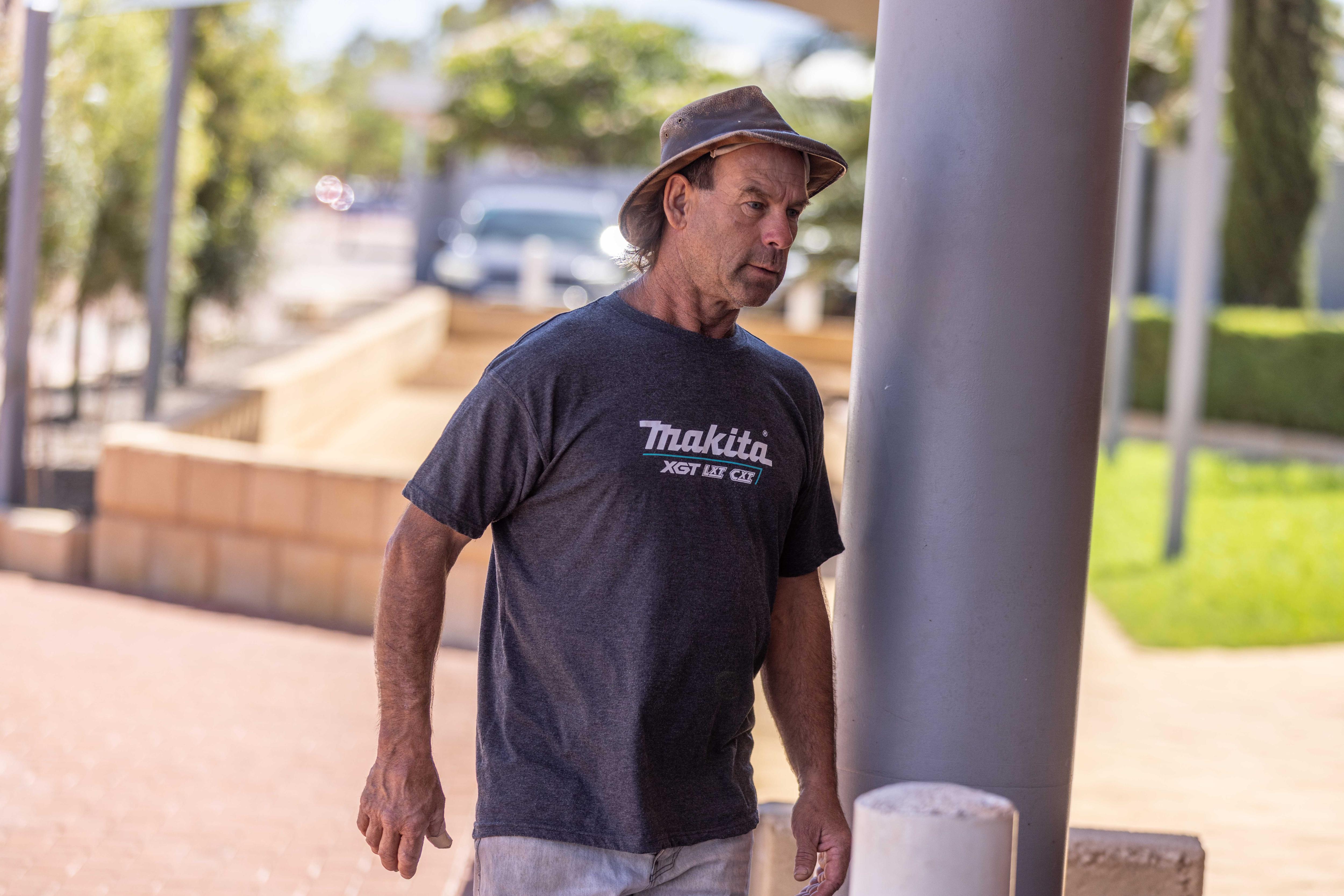 A man wearing a wide-brim hat walks into a police station to report for bail. 