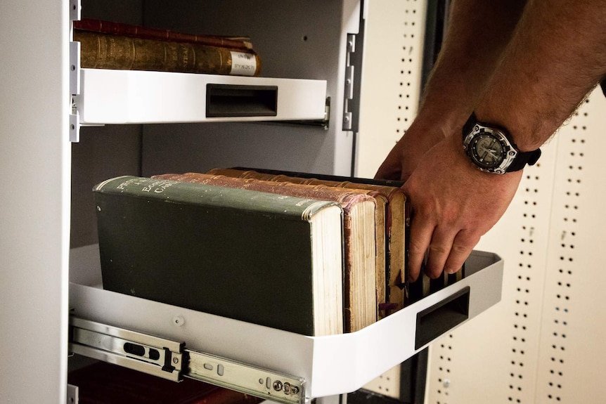 A worker is placing old books on the shelves of a robo-courier.