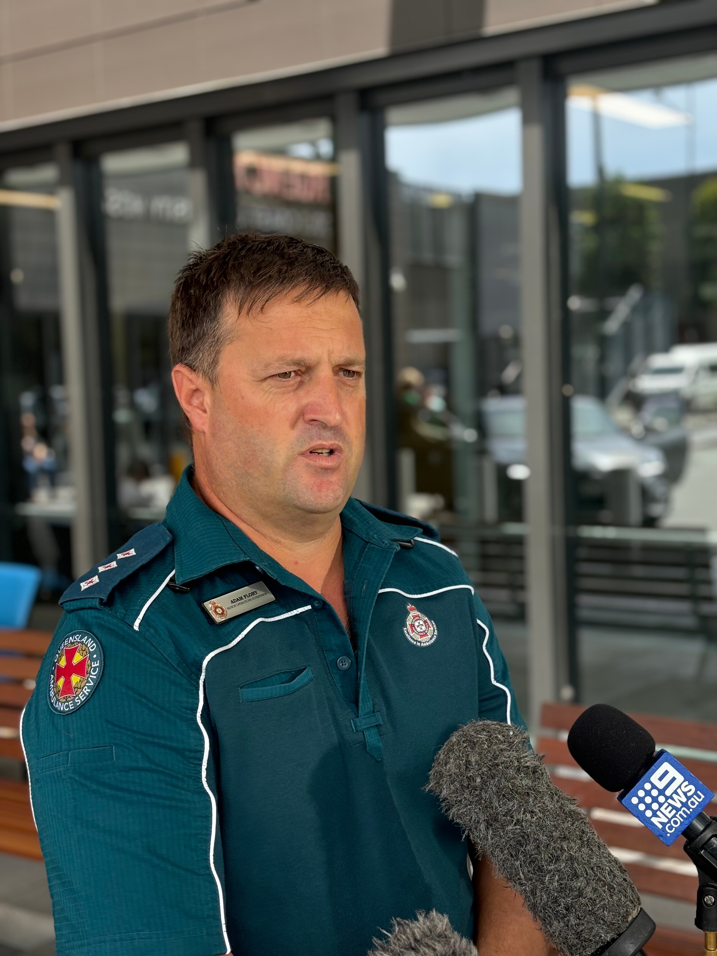 A Queensland Ambulance officer dressed in the service's dark green uniform.