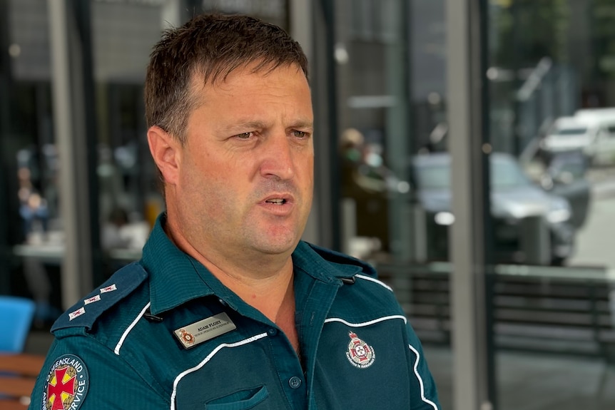 A Queensland Ambulance officer dressed in the service's dark green uniform.