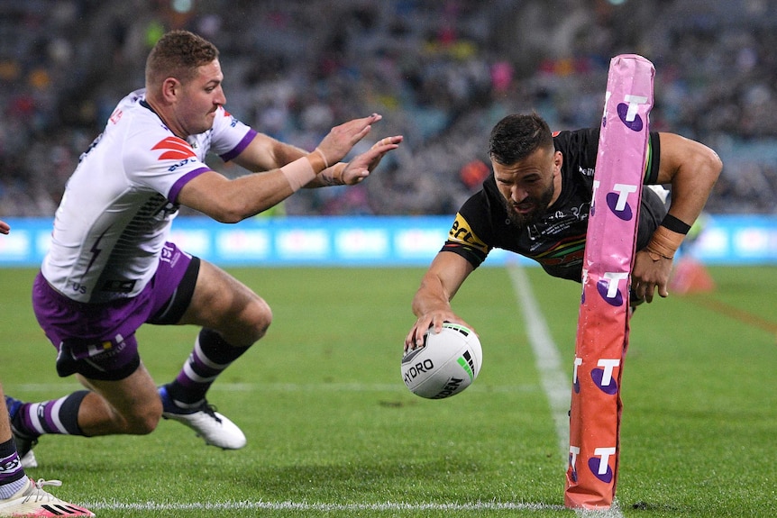 Josh Mansour flies through the air in the corner of the field, with the rugby ball in one hand.