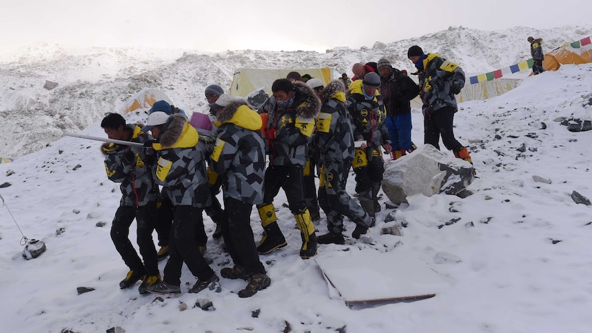 Rescuers stretcher injured to helicopter at Everest base camp