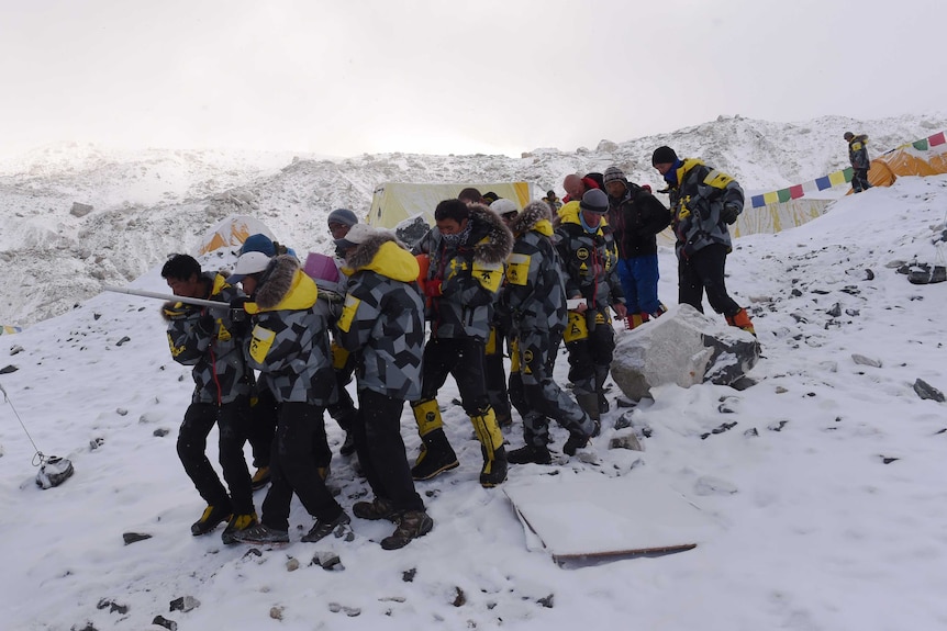 Rescuers stretcher injured to helicopter at Everest base camp