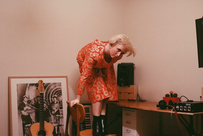 Sydney electronic artist Phebe Starr stands on a chair in front of a guitar and other musical equipment