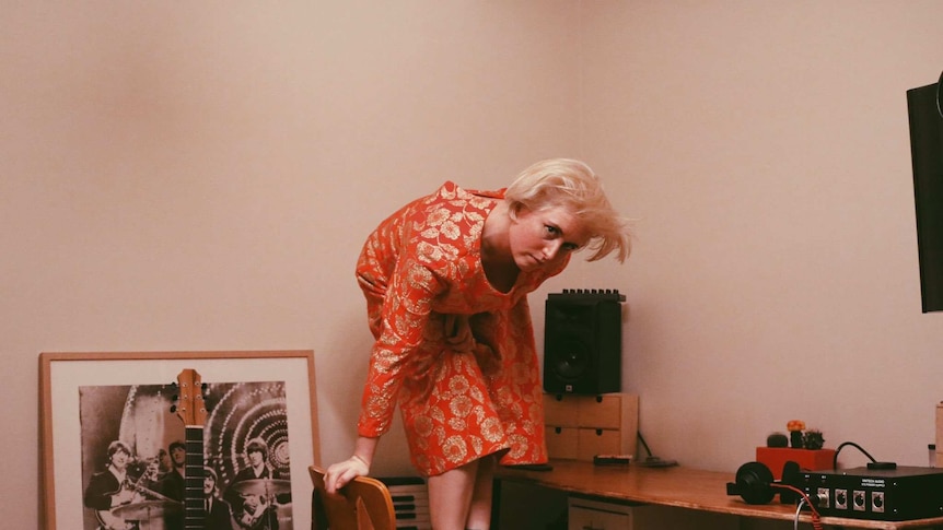 Sydney electronic artist Phebe Starr stands on a chair in front of a guitar and other musical equipment