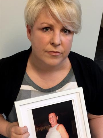 woman hold framed photograph of brother.