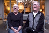 Two men wearing glasses having a big laugh with their mouths open.