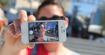 A woman holds an iPhone in front of her face and snaps a selfie.