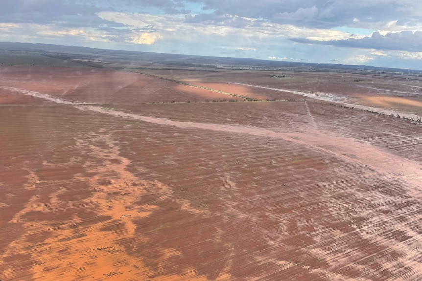 Aerial image of water streaming across orange paddock