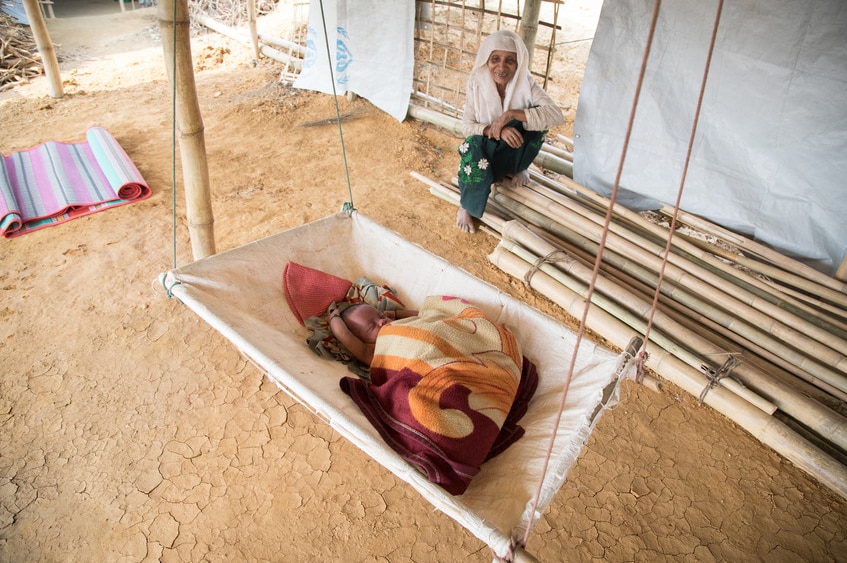 Baby Ismil lying on a book while his grandmother looks on.