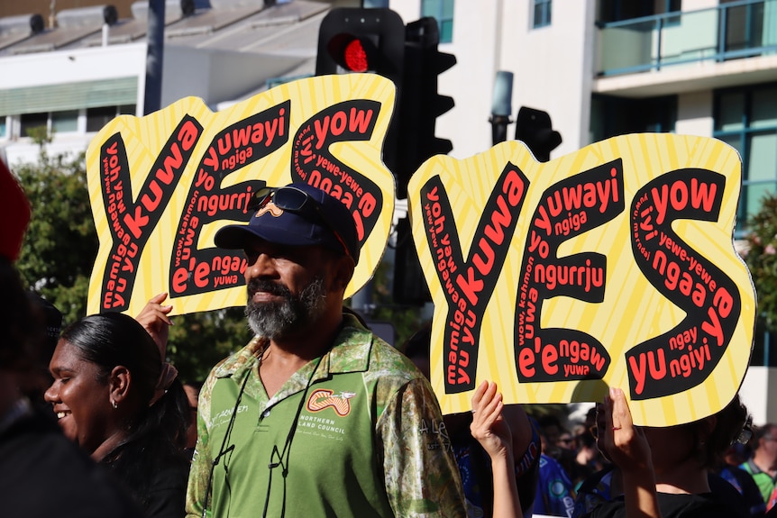 People march in a street holding signs that say 'Yes'