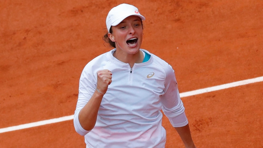 A smiling tennis player clenches her fist and cries out in celebration after clinching major title.