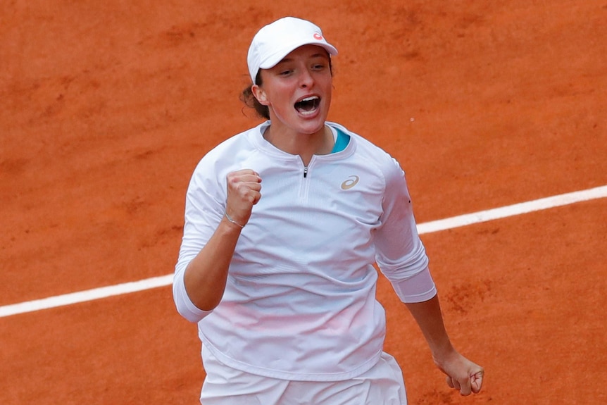 A smiling tennis player clenches her fist and cries out in celebration after clinching major title.