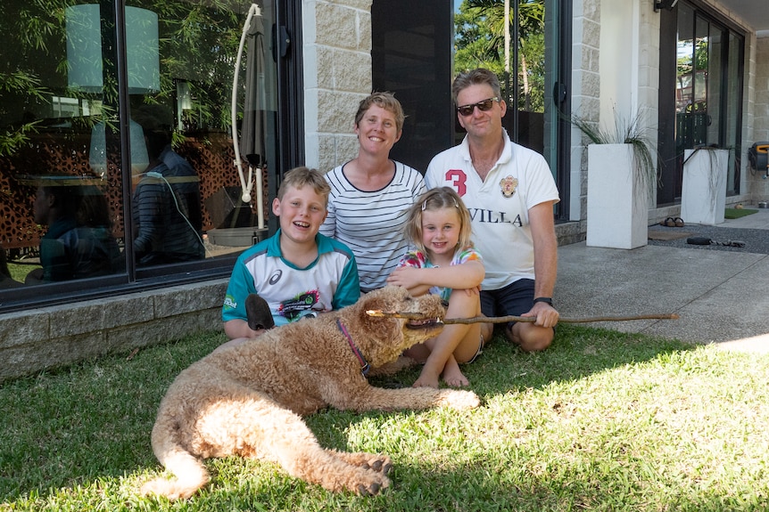 A young family pose for a photo in their garden.