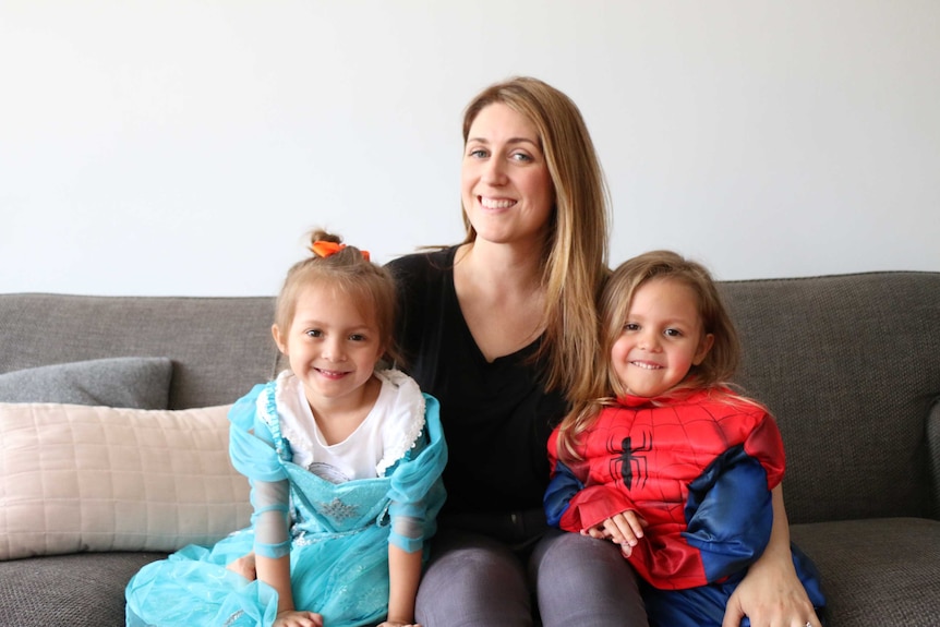 Anna Garcia sits on the couch with her four year old Eva and Sofia.