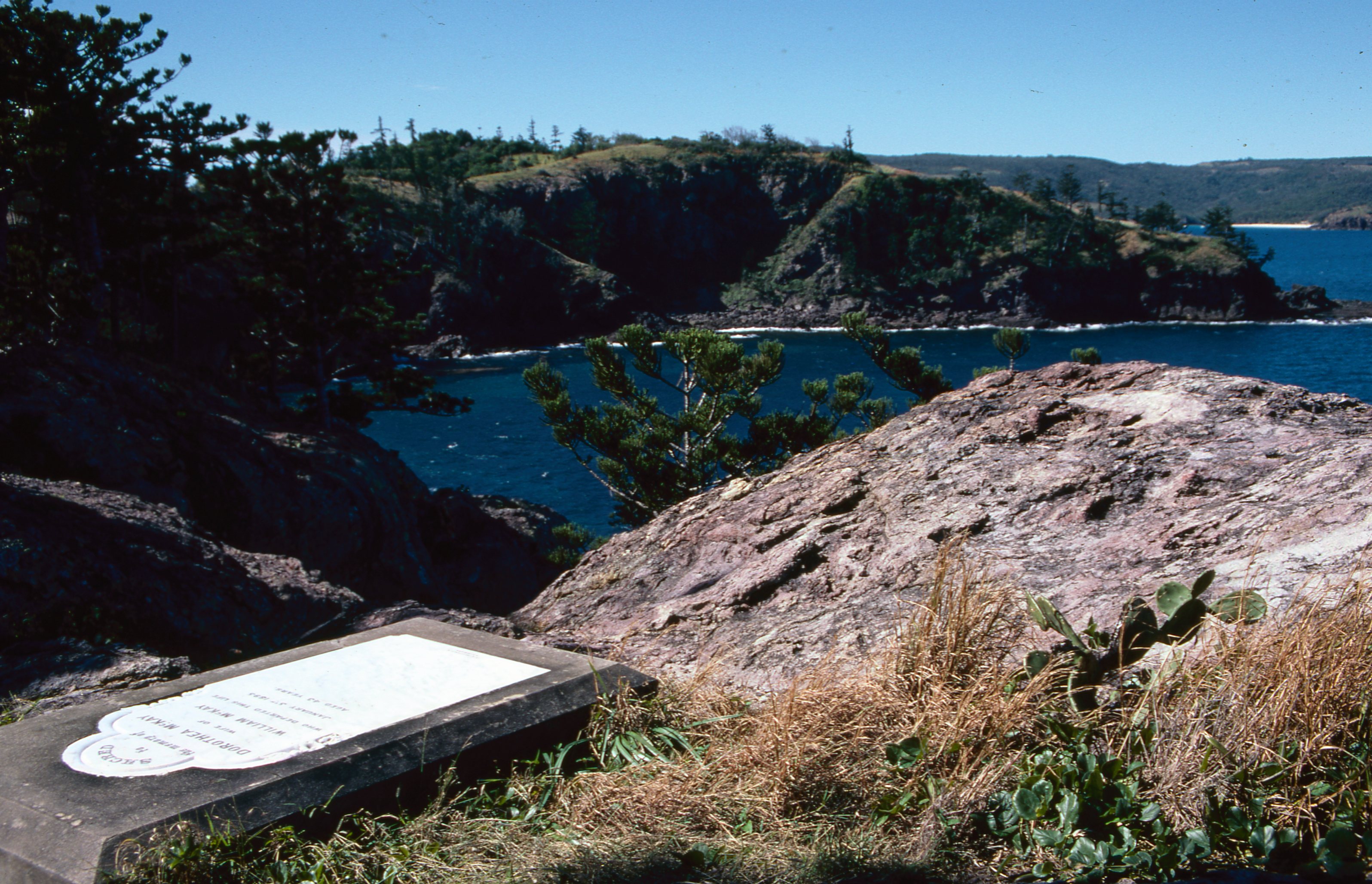 Una lápida de piedra descansa en la cima de una colina en una amplia bahía. 