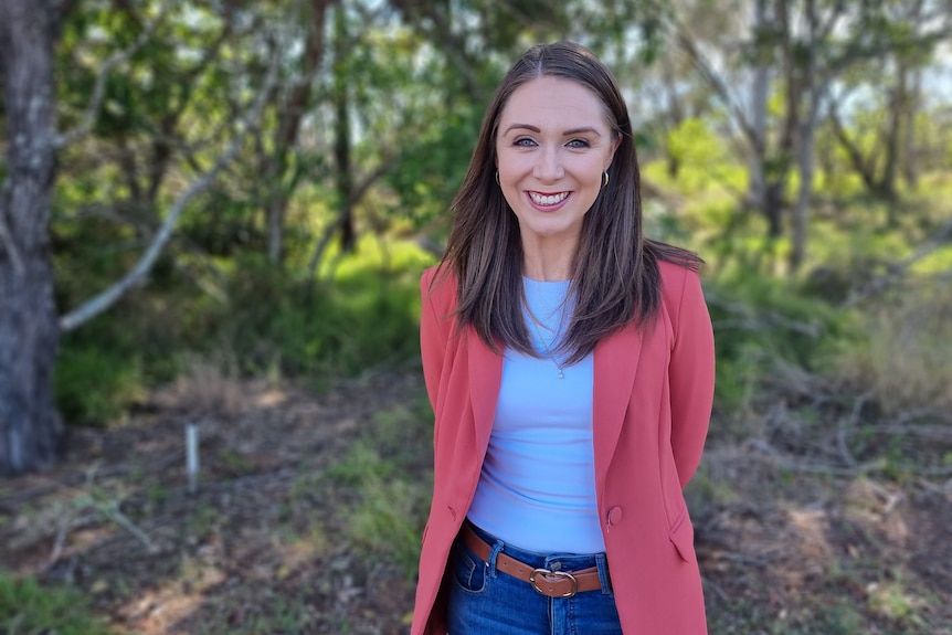 young woman in a pink jacket smiling at for a picture