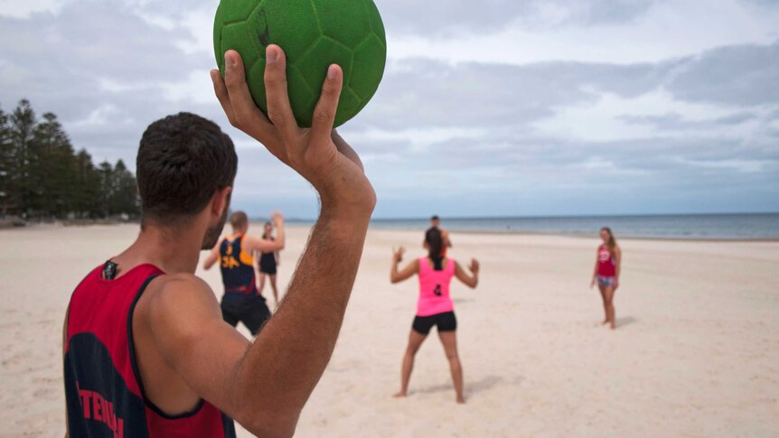 Andrew Antenucci throws a beach handball back into play.
