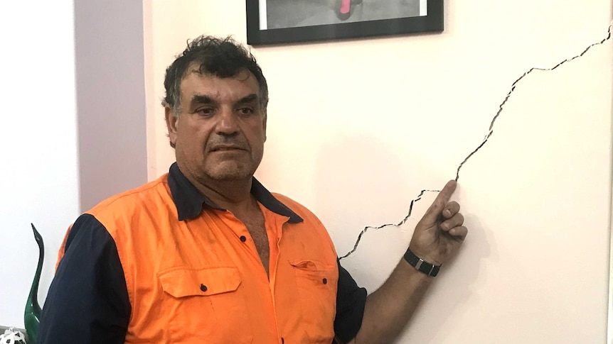 Umberto Galasso pointing to cracks in his home
