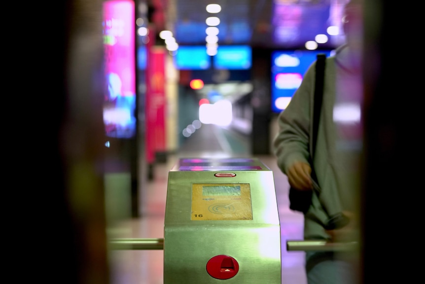 A passenger passes through a turnstile at Adelaide Railway Station.