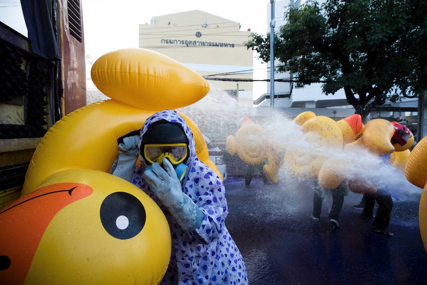 Pro-democracy protesters take cover with inflatable ducks as police fire a water cannon.