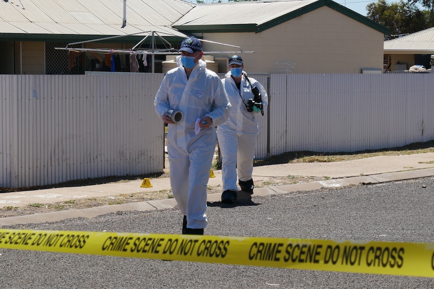 Two crime scene investigators in white protective gear walks out of a house towards crime tape