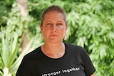 Stacey Ross from the Centre for Women wears a black shirt that says stronger together while standing in front of a tree.