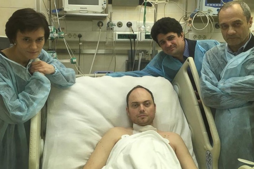 A man in a hospital bed surrounded by three people in scrubs